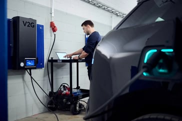 Virta Techniker testet Virta V2G an einem E-Auto, das mit einer V2G Ladestation verbunden ist.