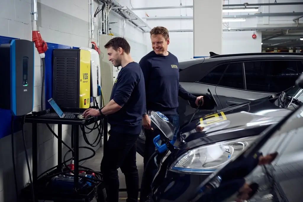Zwei Virta Mitarbeiter testen Virta V2G an einer Ladestation in einer Garage