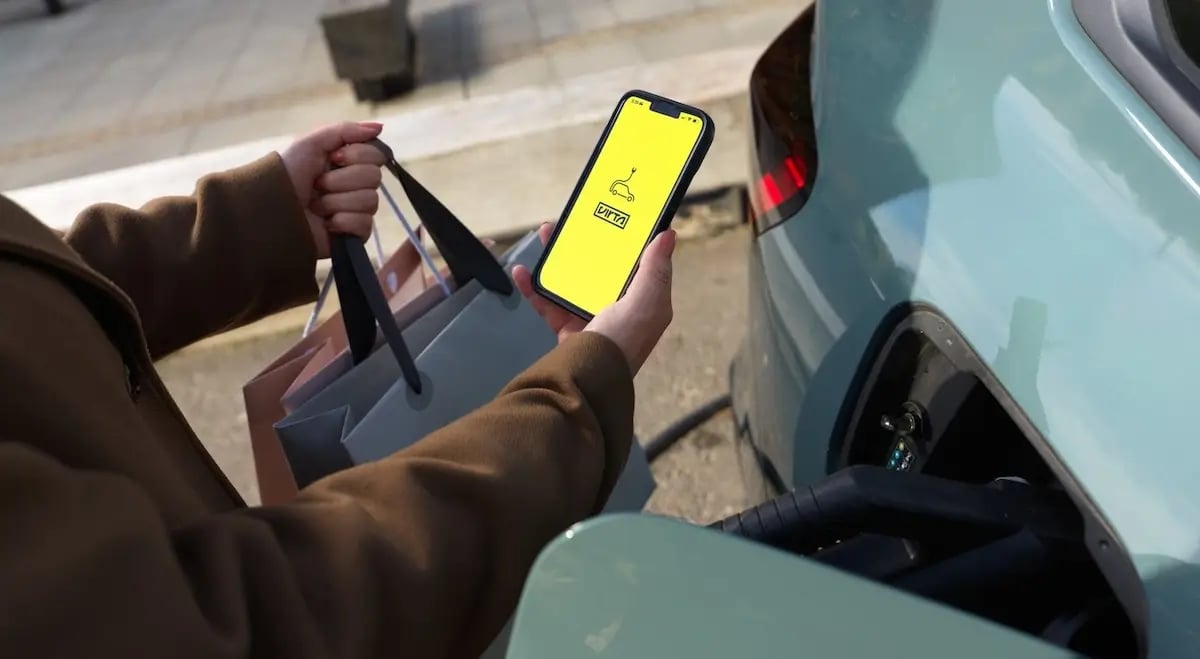 Junge Frau mit Einkaufstüten nutzt das Laden von E-Autos als Value Added Service im Einzelhandel und lädt ihr E-Auto mit der Virta App auf.