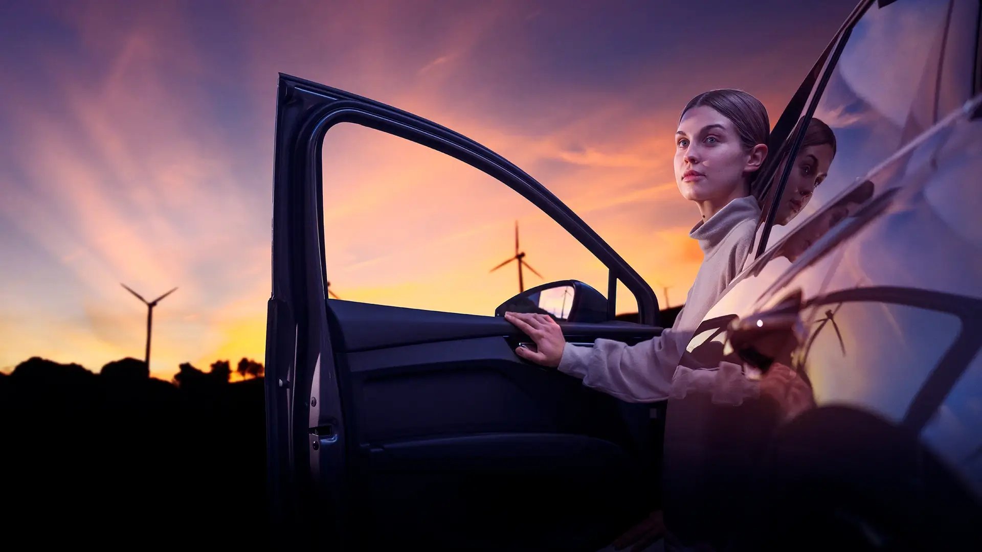 Självförtroendefull kvinna i elbil med vindturbin i soluppgången