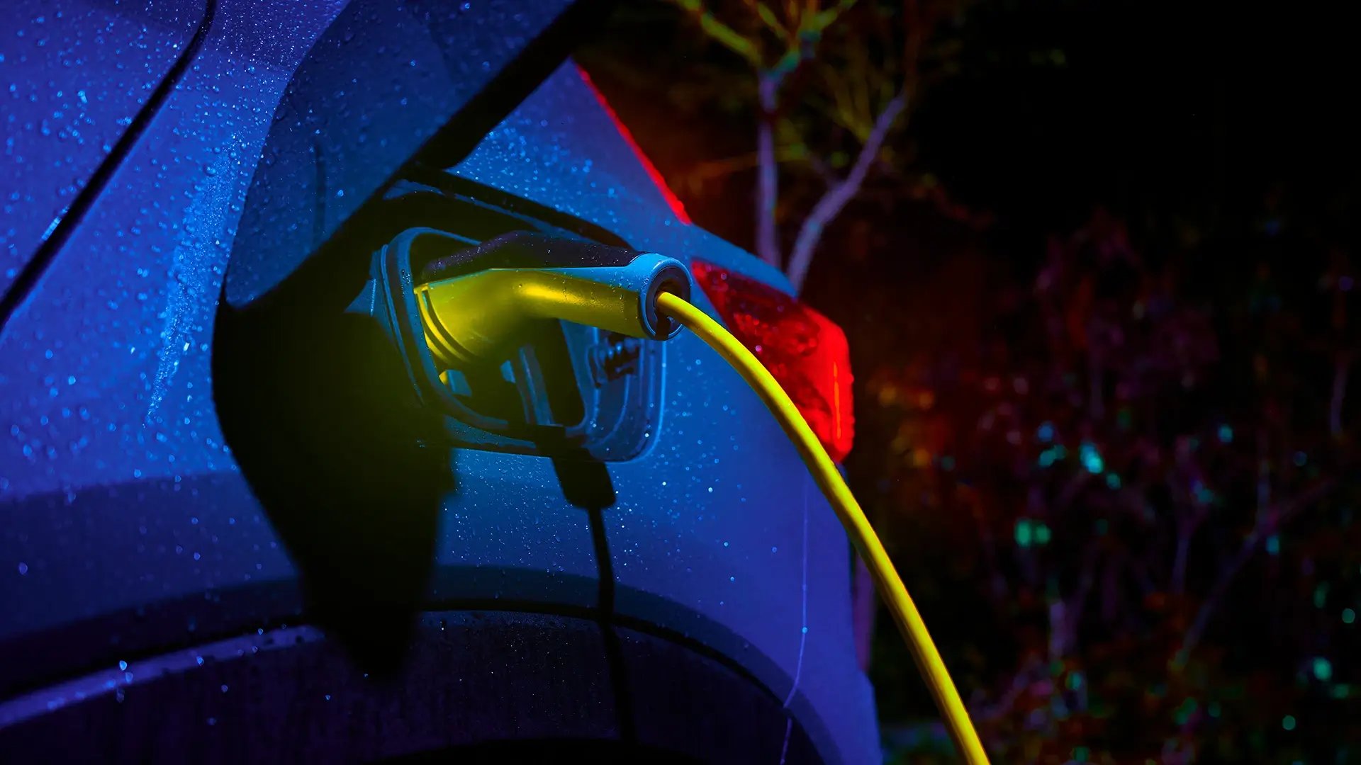 Nighttime EV charging with raindrops on car