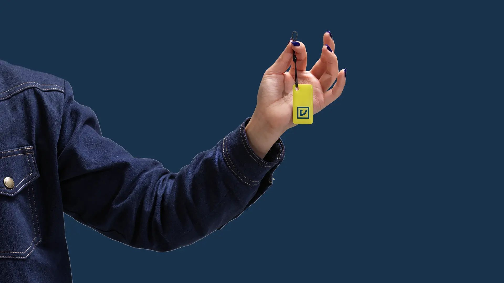 Käsi joka pitelee Virran RFID-lataustunnistetta, sininen tausta