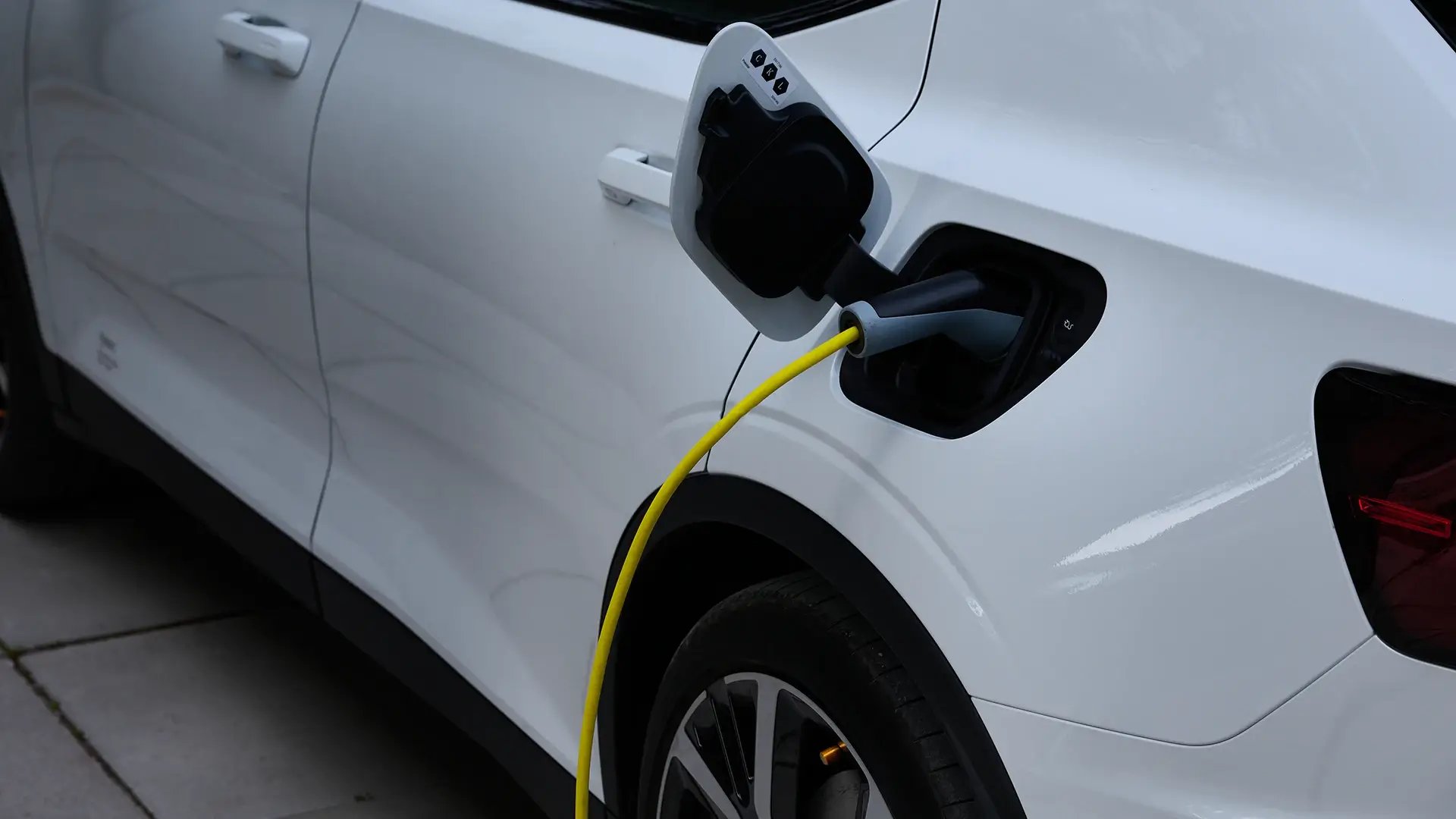 Weißes E-Auto steckt an Ladestation mit gelbem Ladekabel