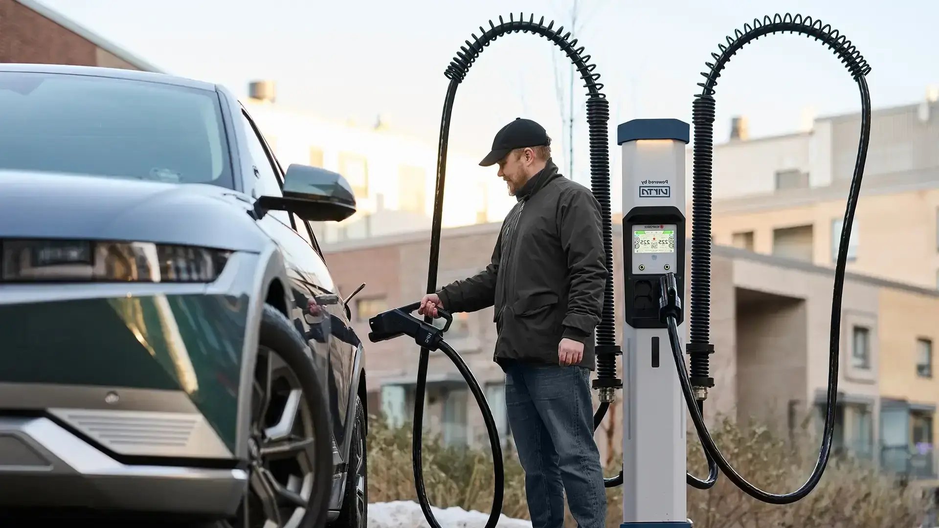 Man charging an electric vehicle at a public DC fast charging station