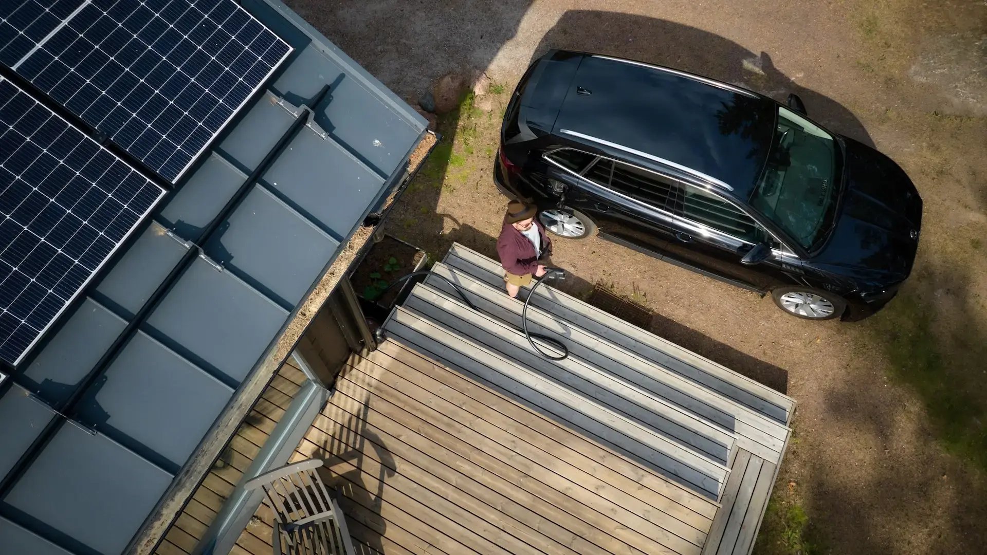 Mann lädt E-Auto mit Solarstrom von Photovoltaik-Anlage auf Dach