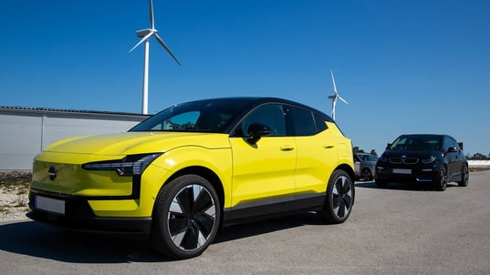 Yellow and black EVs with wind turbines and blue sky
