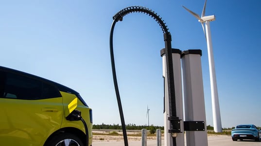 Yellow and blue EVs side view HPC charging station with wind turbine and blue sky