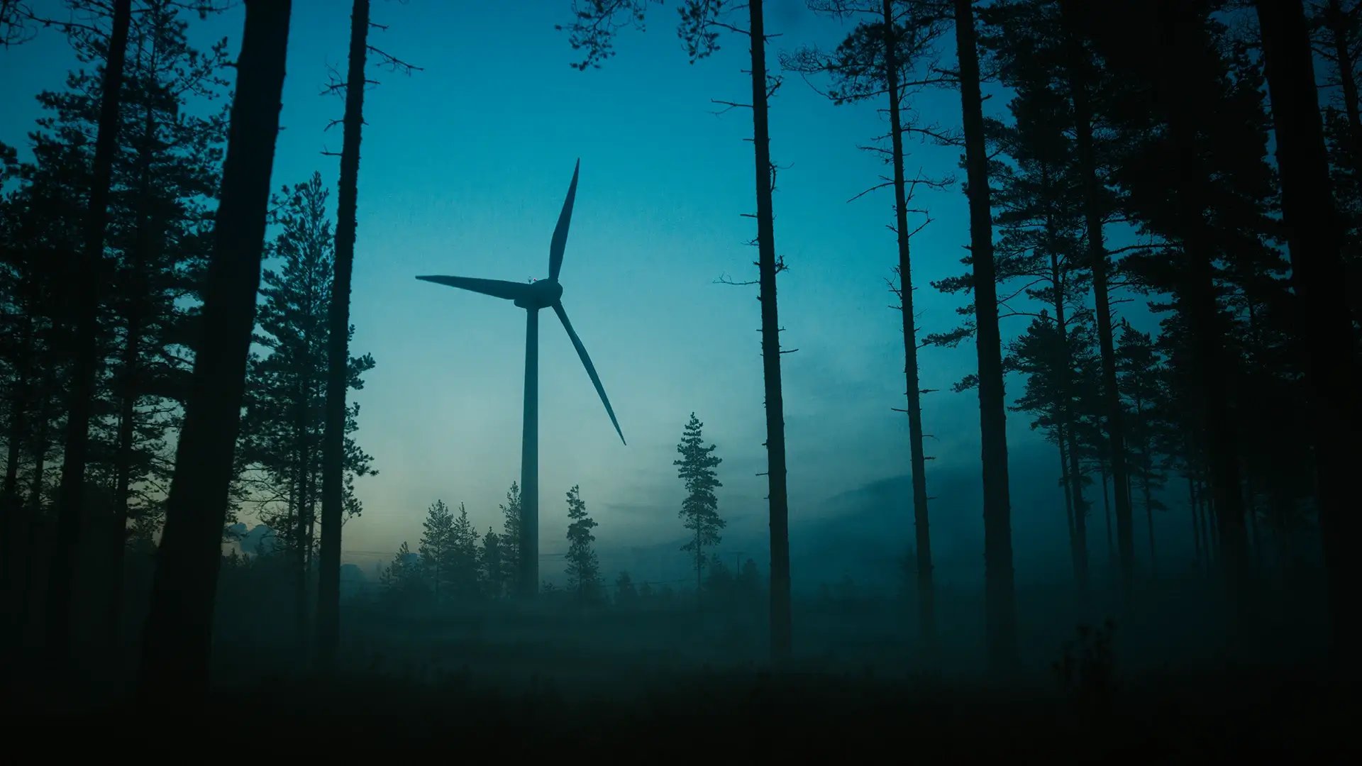 Windkraftanlage steht in einem nebeligen Wald zur Morgendämmerung