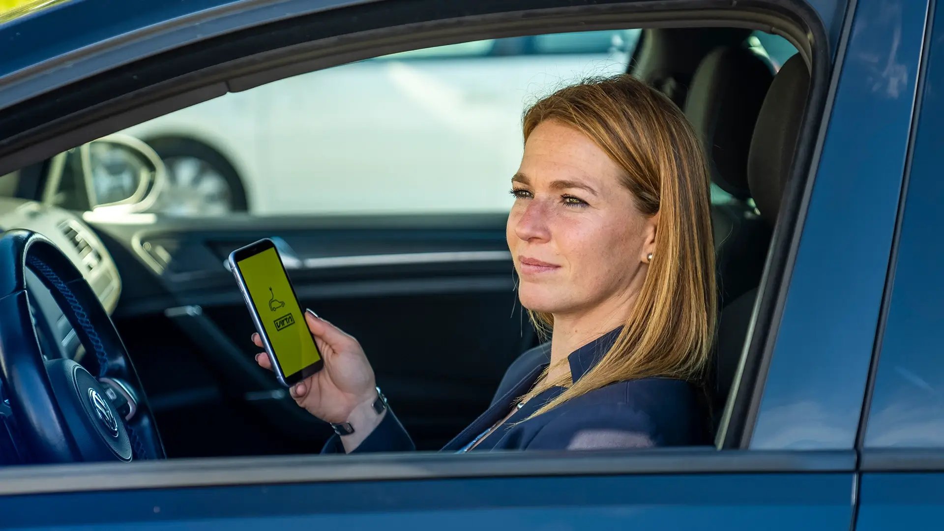 Une femme utilise un smartphone dans une voiture électrique