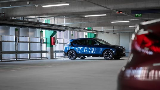 Blaues E-Auto lädt an AC-Ladesäule in Parkgarage