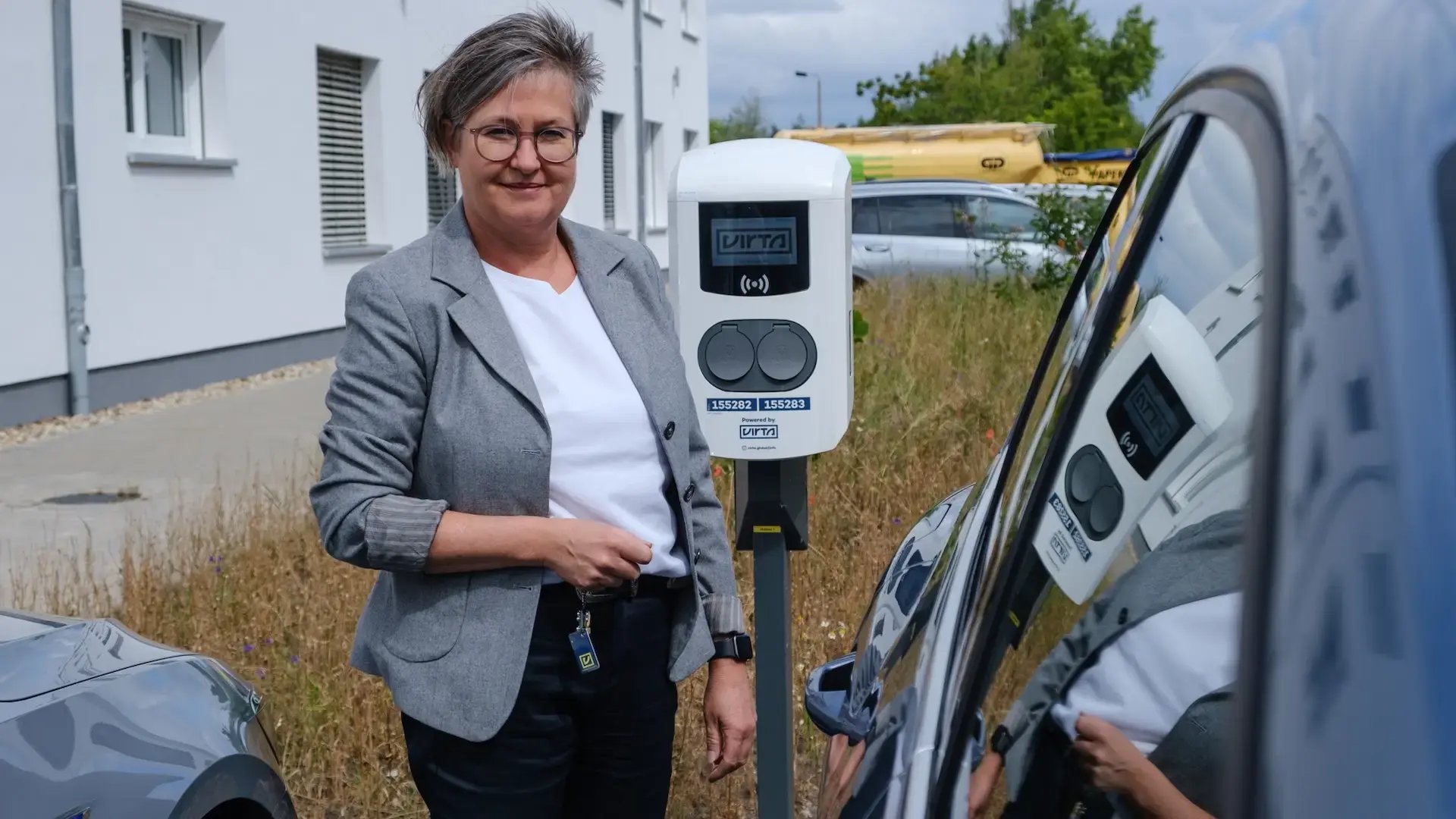 Angela Papenburg board member of GP Papenburg AG holding Virta RFID-tag next to EV and Virta charging station