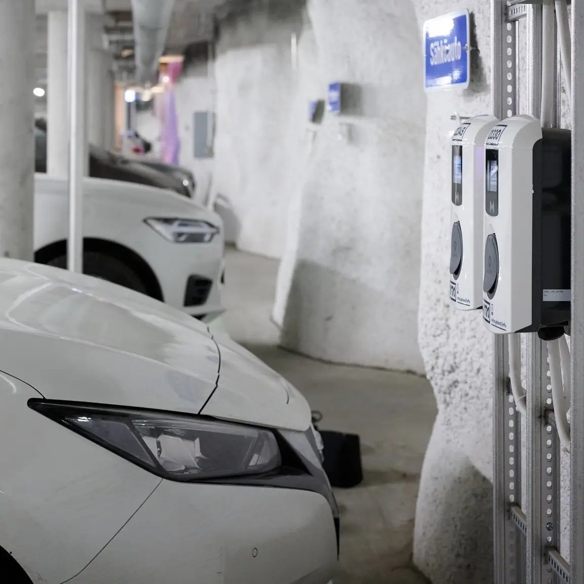 Elektrofahrzeuge laden an AC-Ladestationen in einem weißen Parkhaus
