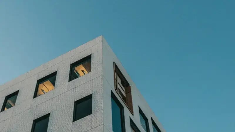 Modern office building exterior with large windows against a blue sky