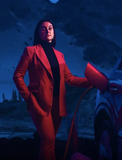 Kvinna klädd i röd kostym som laddar en elbil