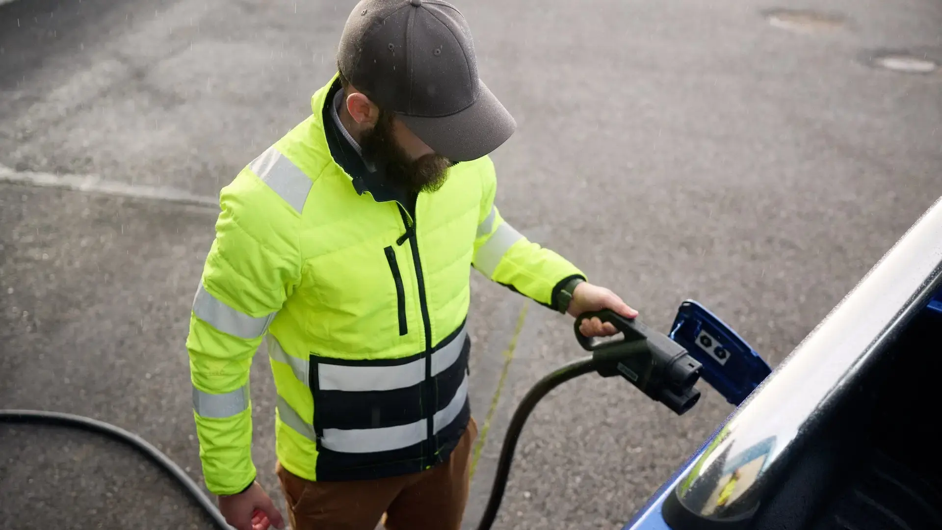 Mann mit gelber Weste hält CCS Stecker an elektrisches Nutzfahrzeug