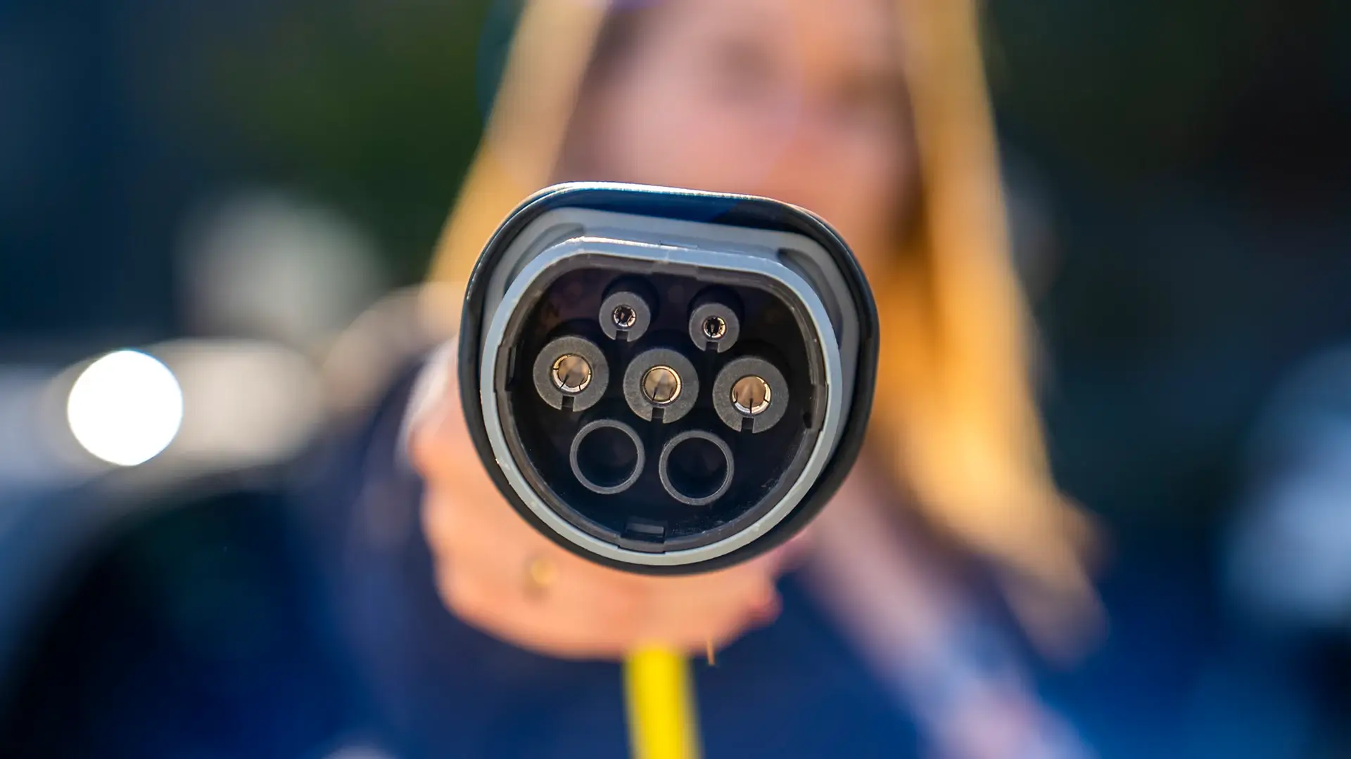 Frau hält Typ 2 Stecker Ladekabel für E-Auto in die Kamera