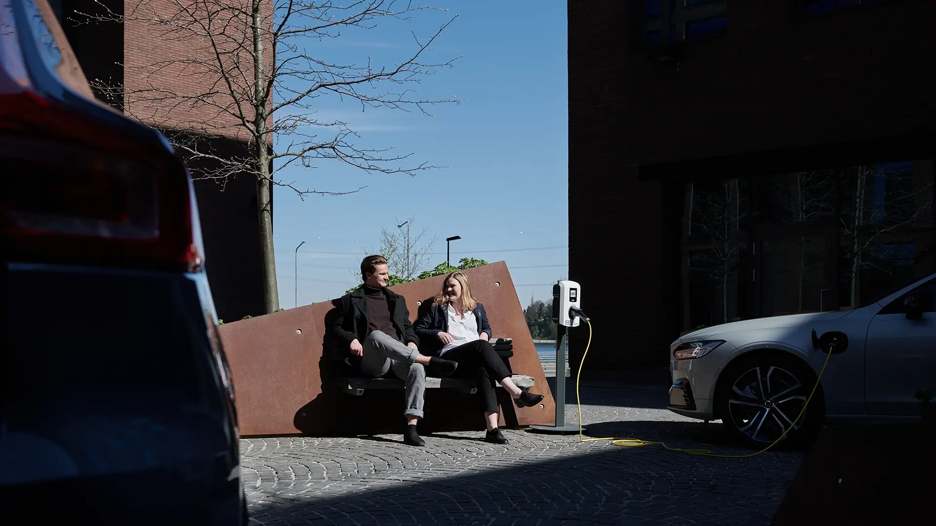Couple enjoying coffee while electric vehicle charges urban setting