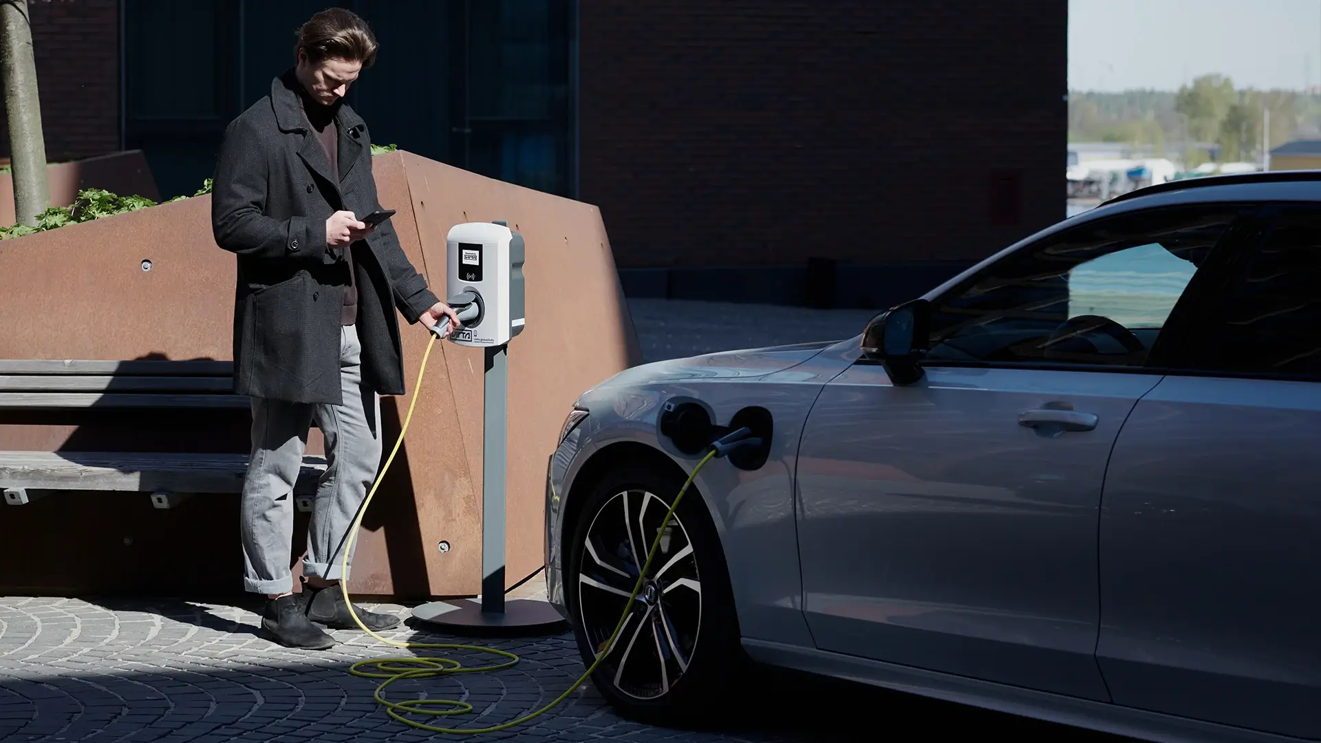 Man charging electric car public outside workplace