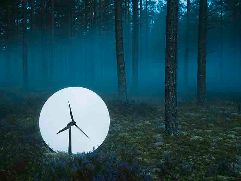 Foto på en skog i skymningen med ett vindkraftverk i fokus